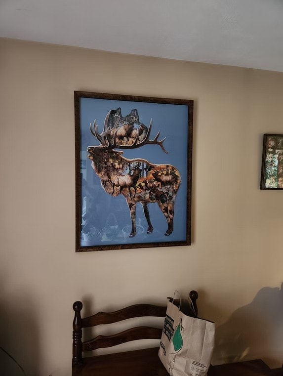 Framed elk wildlife puzzle artwork displayed on a living room wall