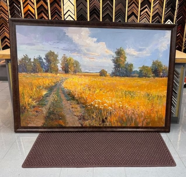 Framed oil painting of a golden wheat field with trees displayed in the shop