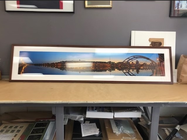 Extra-wide panoramic cityscape photograph custom framed in a walnut frame