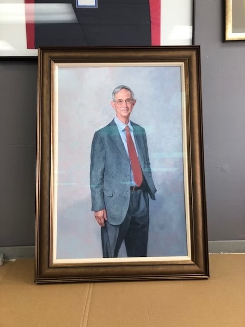 Framed formal portrait of a man in a gray suit